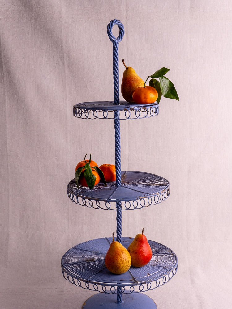 Antique French blue three-tier wirework pastry display stand with pears and small orange fruits.
