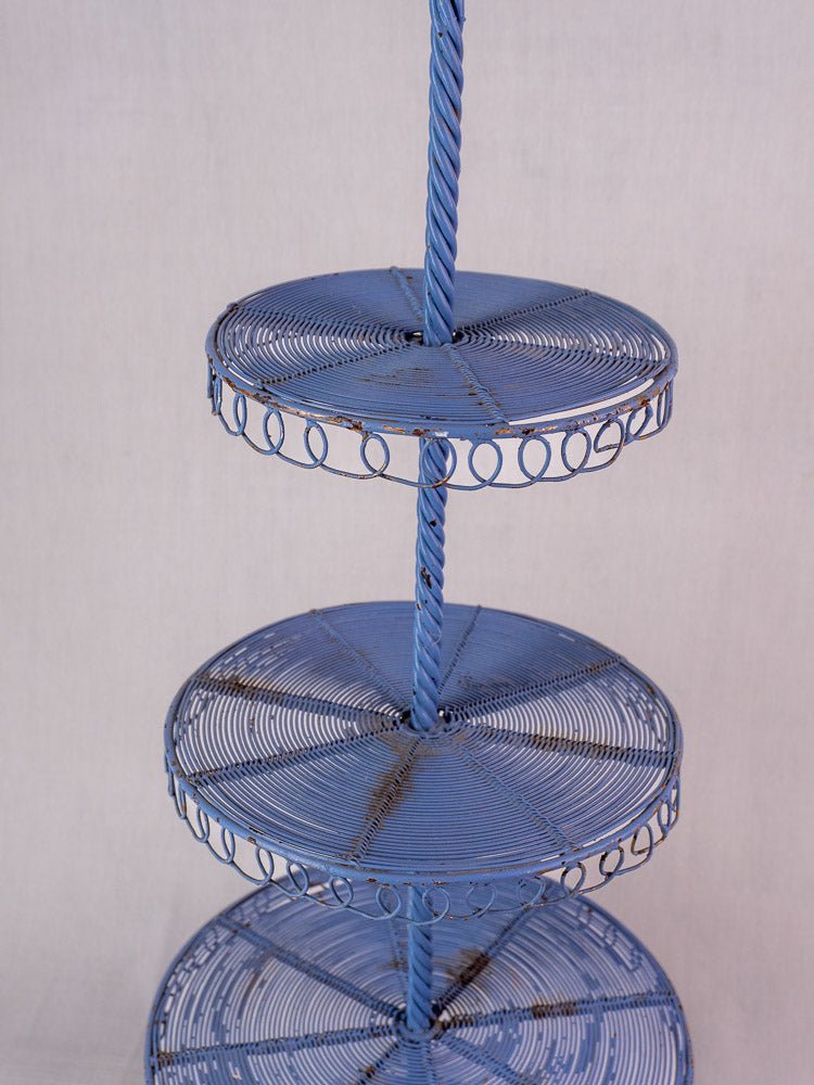 Antique French blue wirework pastry display stand with three tiers and twisted central rod.
