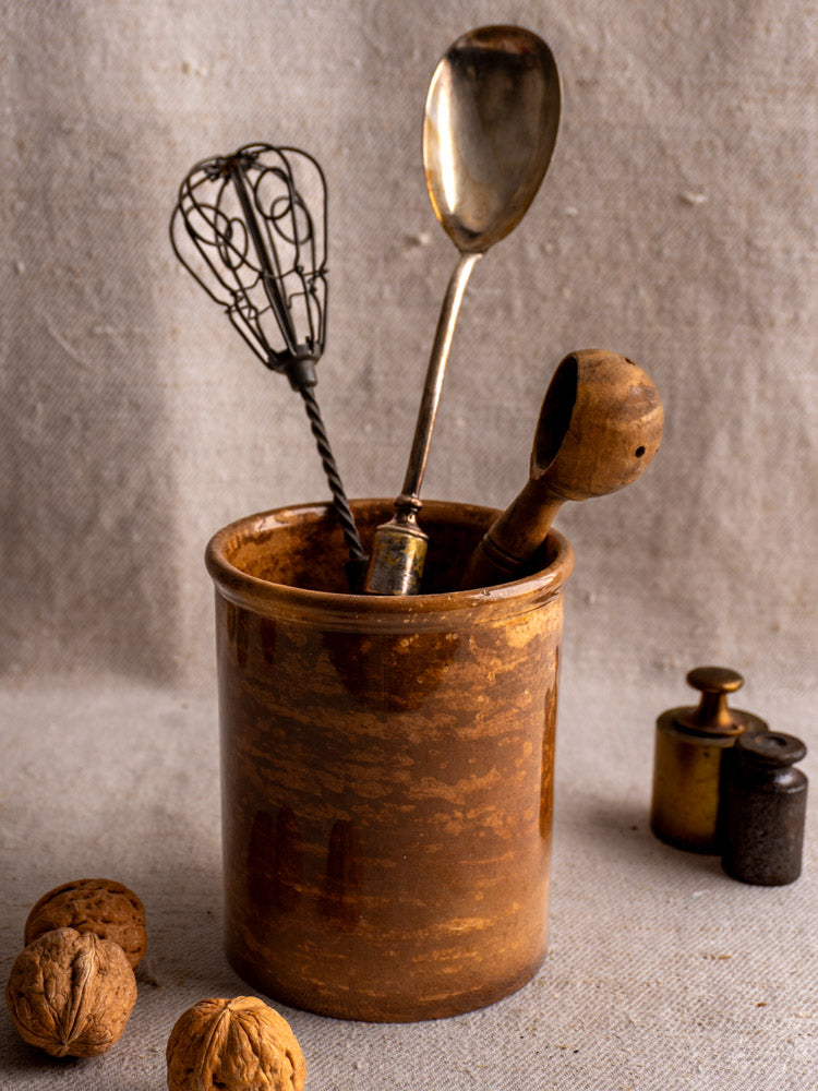 Antique French Creil et Montereau confit pot with brown glaze, holding utensils; walnuts and weights nearby.