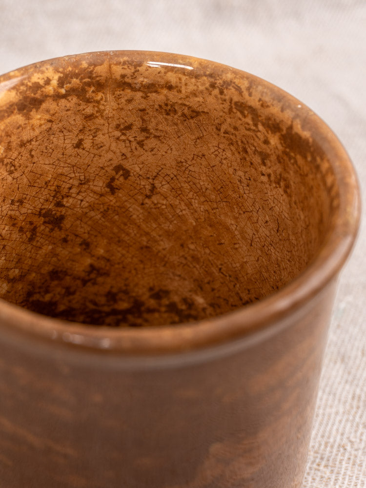 Antique French Creil et Montereau confit pot with brown glaze, rustic speckled interior on light fabric.