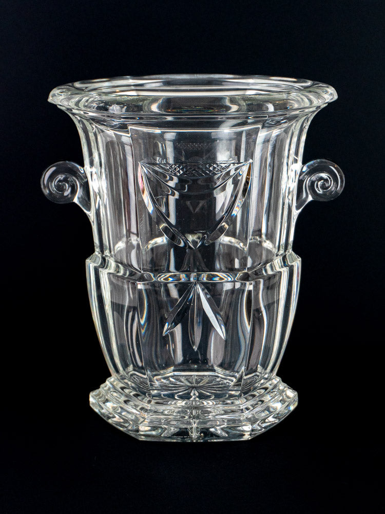 French cut crystal champagne bucket with ornate handles and geometric patterns on black background.