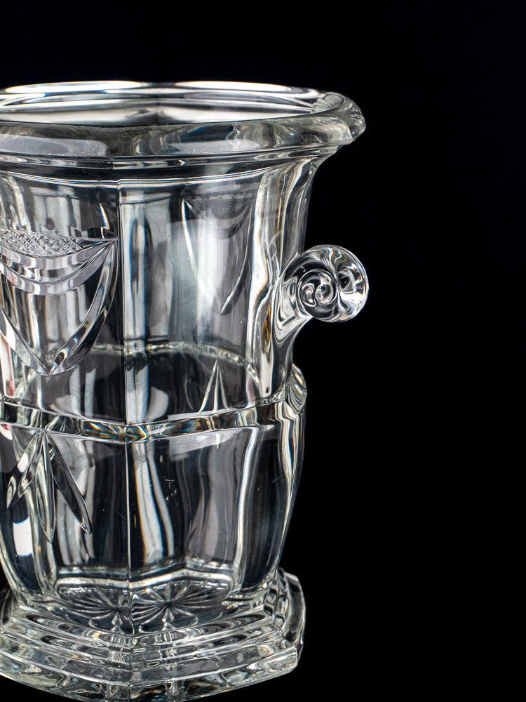 Vintage French cut crystal champagne bucket with ornate right-side handle, displayed on a black background.