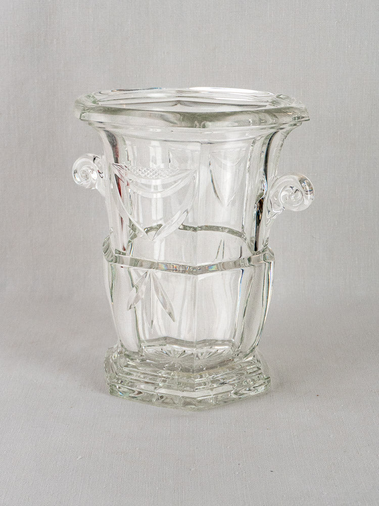 Vintage French cut crystal champagne bucket with etched patterns and twin decorative handles on gray surface.