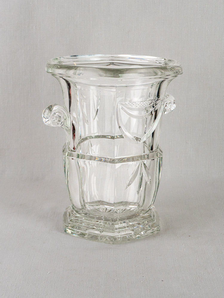 Vintage French cut crystal champagne bucket with decorative handles and etched detailing on neutral gray background.