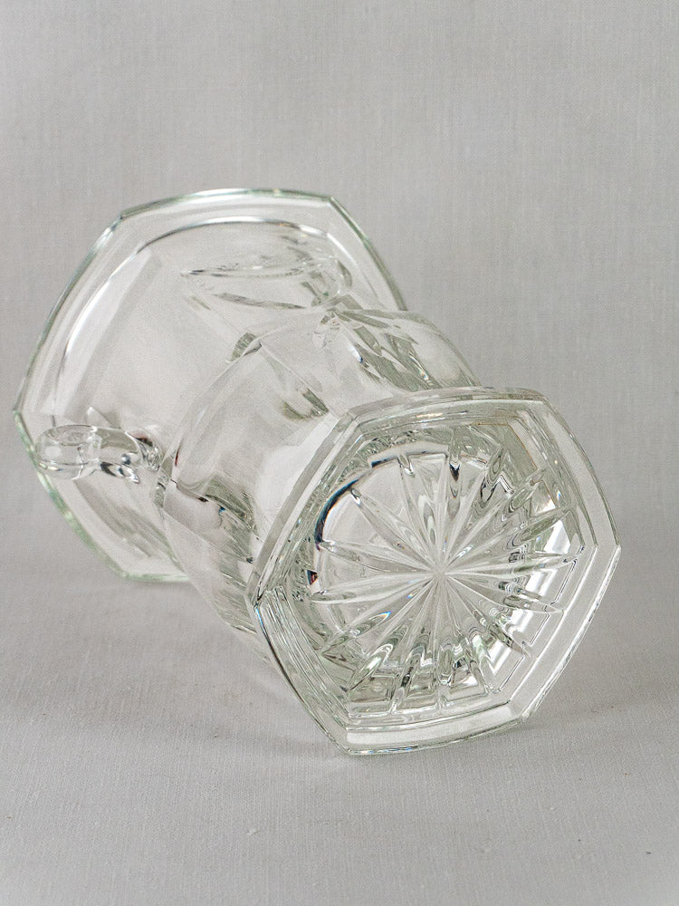 Vintage French cut crystal champagne bucket with hexagonal base and starburst design on light background.