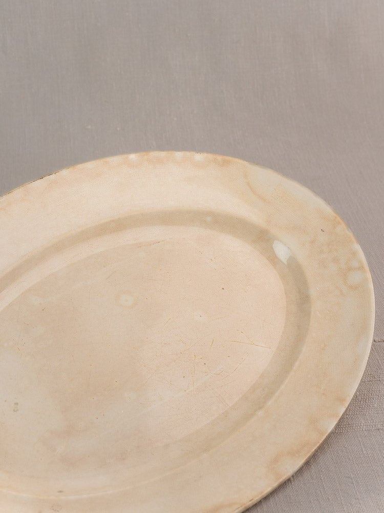 Vintage French Digoin & Sarreguemines ivory ironstone oval platter with aged patina on light gray surface.
