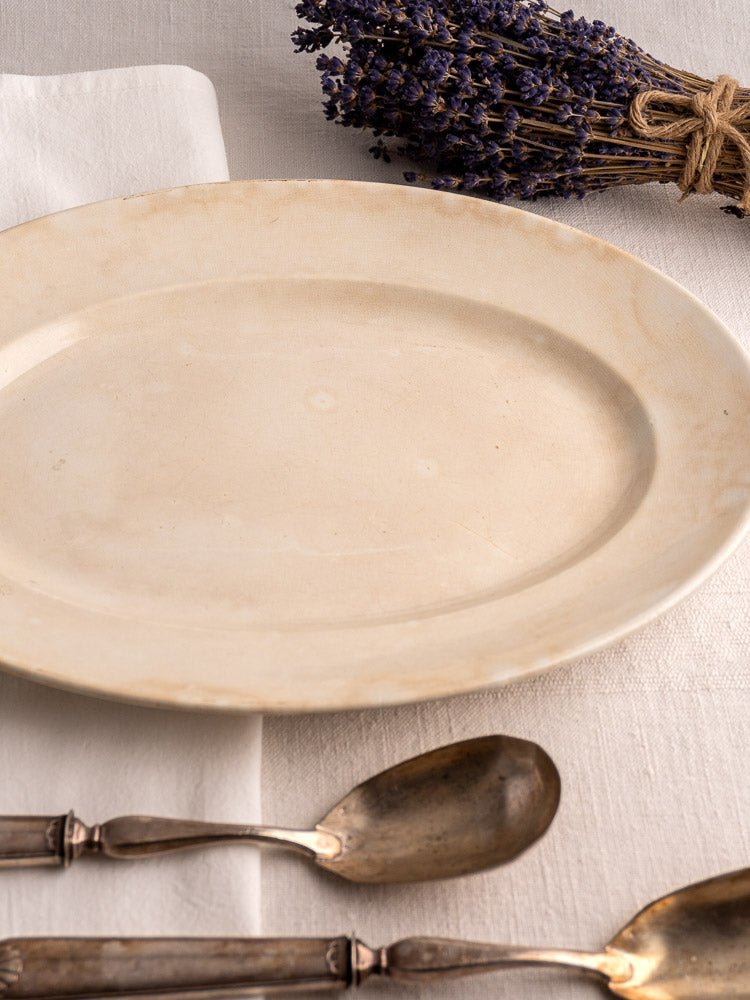 Vintage French Sarreguemines ivory ironstone platter on white cloth with silverware and dried lavender.