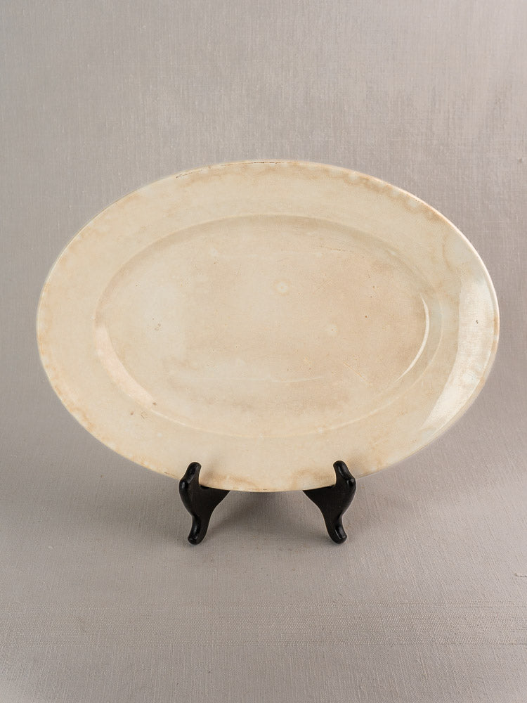 Oval ivory vintage French Digoin & Sarreguemines ironstone platter with light discoloration on black stand.
