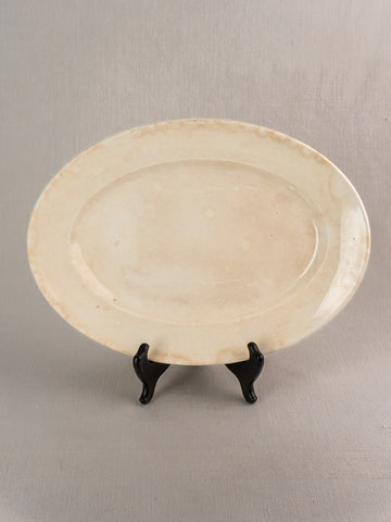 Oval ivory vintage French Digoin & Sarreguemines ironstone platter with light discoloration on black stand.
