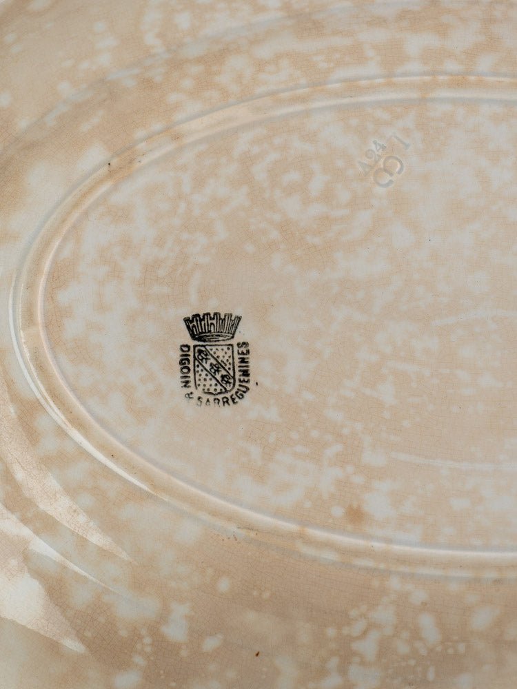Underside of vintage French Sarreguemines ivory ironstone platter with speckled beige, crest mark, and number 894.