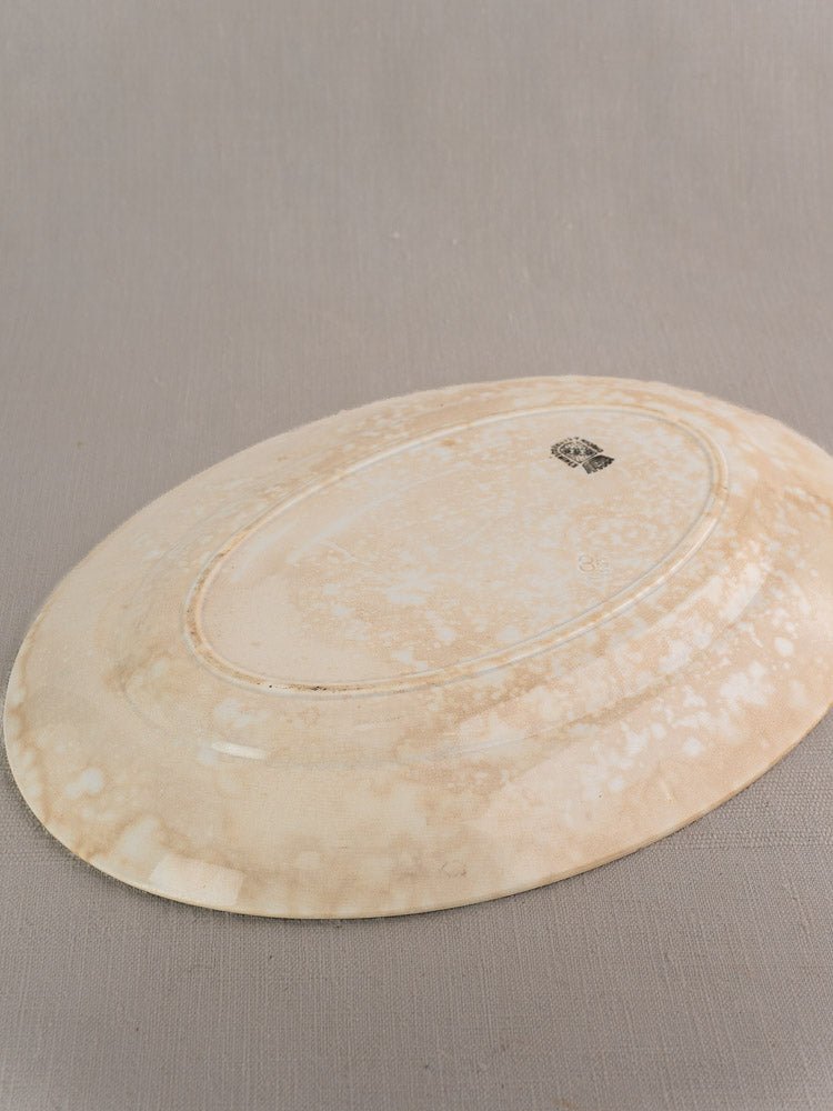 Large oval ivory French ironstone platter, Digoin & Sarreguemines, on gray fabric, visible mottling.