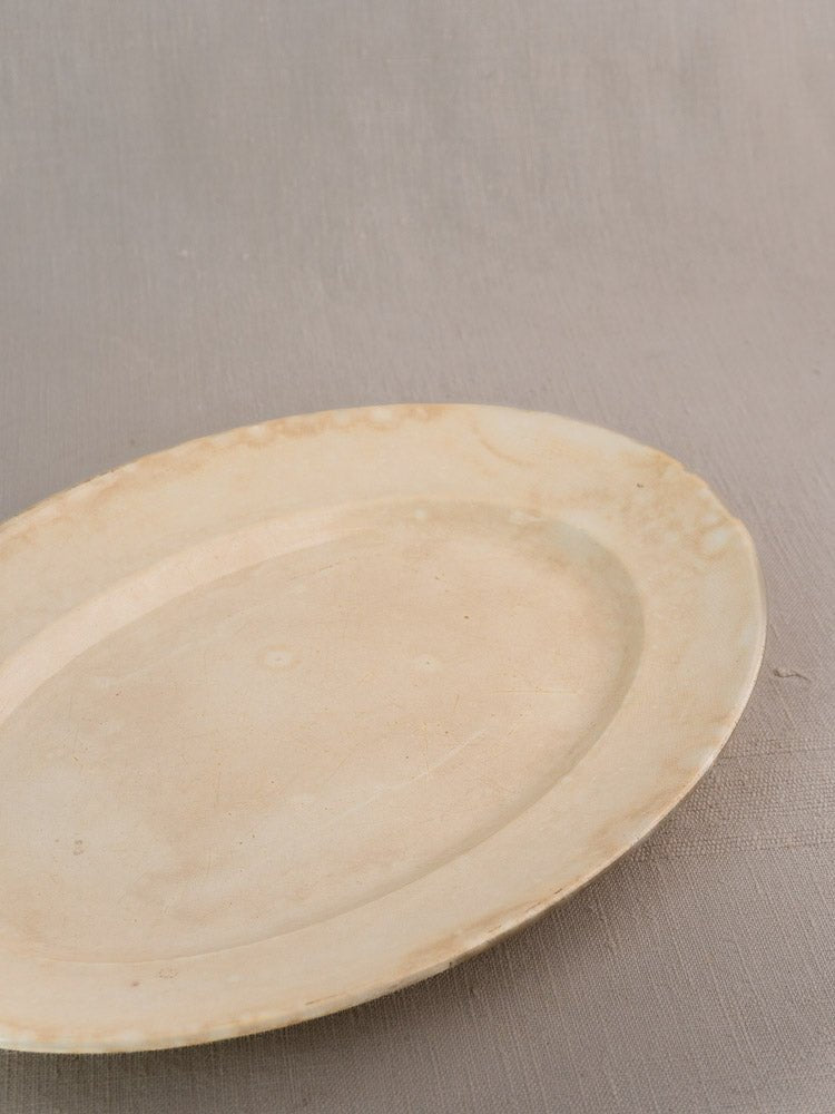 Vintage French Sarreguemines ivory ironstone oval platter with light discoloration on gray surface.