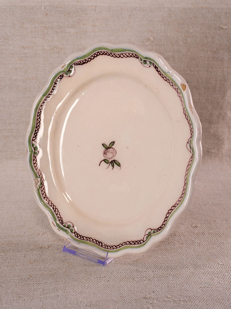 Pair of antique French faience plates with hand-painted turnip motifs on clear stands, beige fabric backdrop.