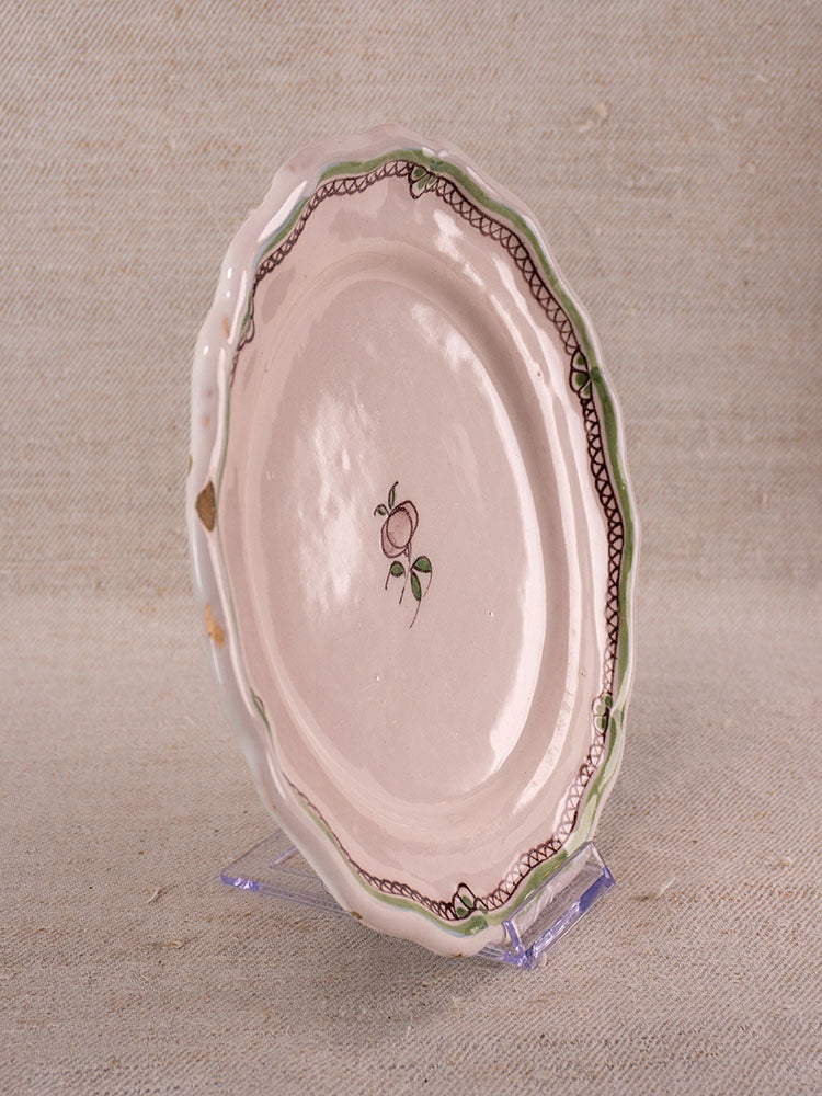 Pair of antique French faience plates with hand-painted turnip motif, scalloped edges, pale pink glaze on clear stands.