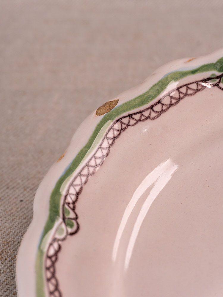 Antique French faience plate with scalloped rim, hand-painted turnip motif, green-brown border, chip on beige background.
