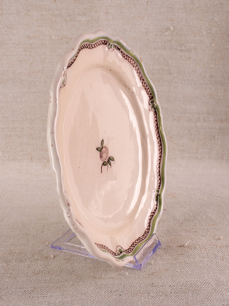 Antique French faience plate with hand-painted turnip, scalloped edges, wavy brown border, green accents on clear stand.