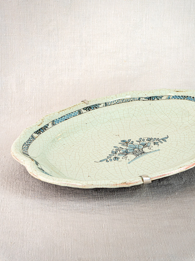 Oval Rouen-style faience platter with blue floral motifs, tin-glazed earthenware, on neutral background.