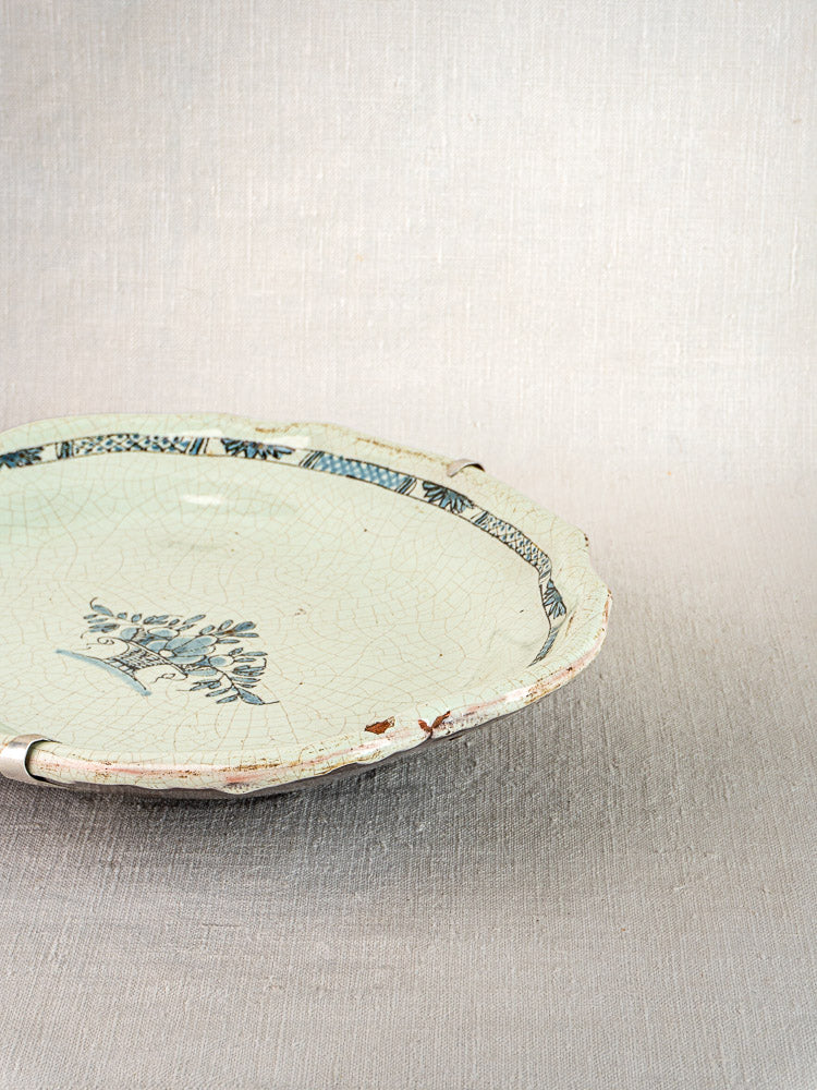 Antique French faience platter with blue floral motif, decorative border, and aged patina on ceramic.