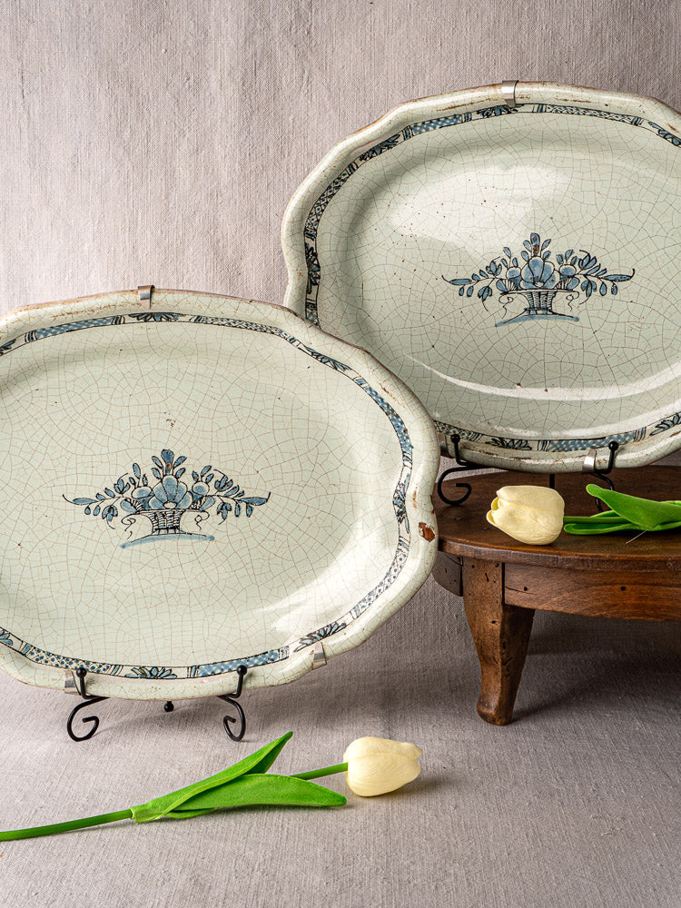 Pair of antique French Cul Noir faience platters with blue floral motifs, displayed with yellow tulips.