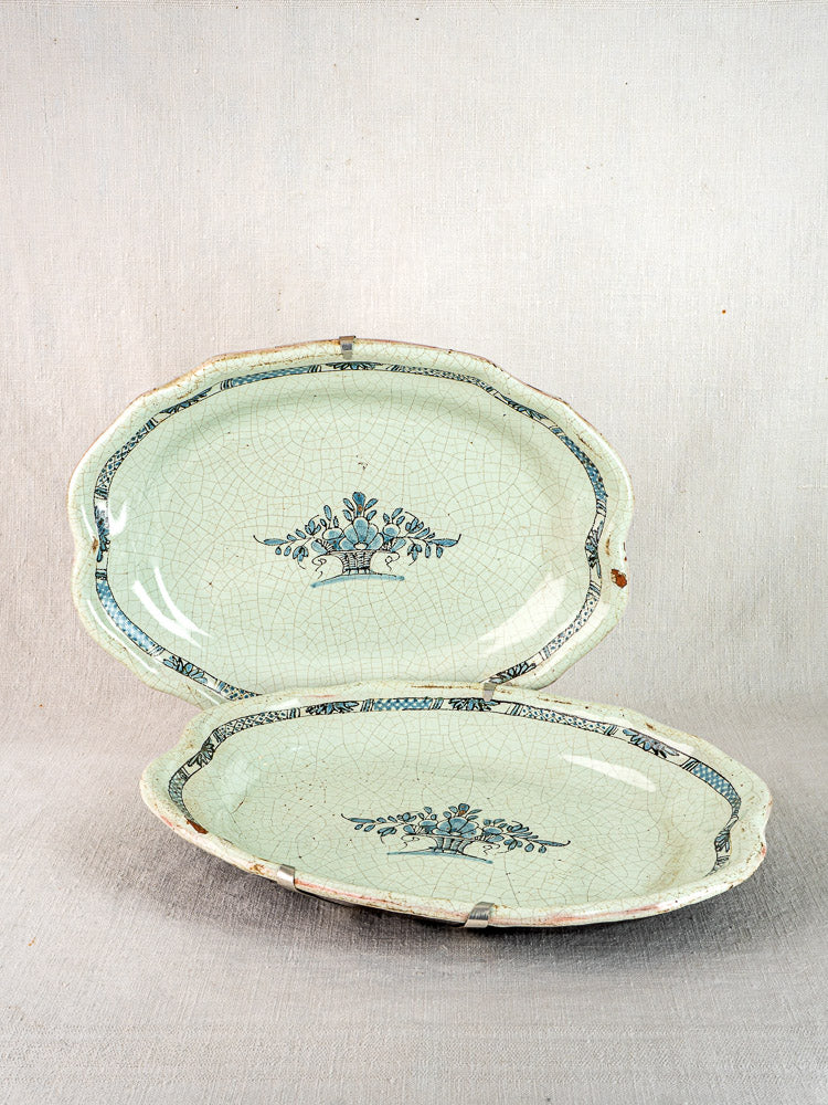 Pair of antique French Cul Noir faience platters, Rouen style, with blue floral motifs and cracked glaze.