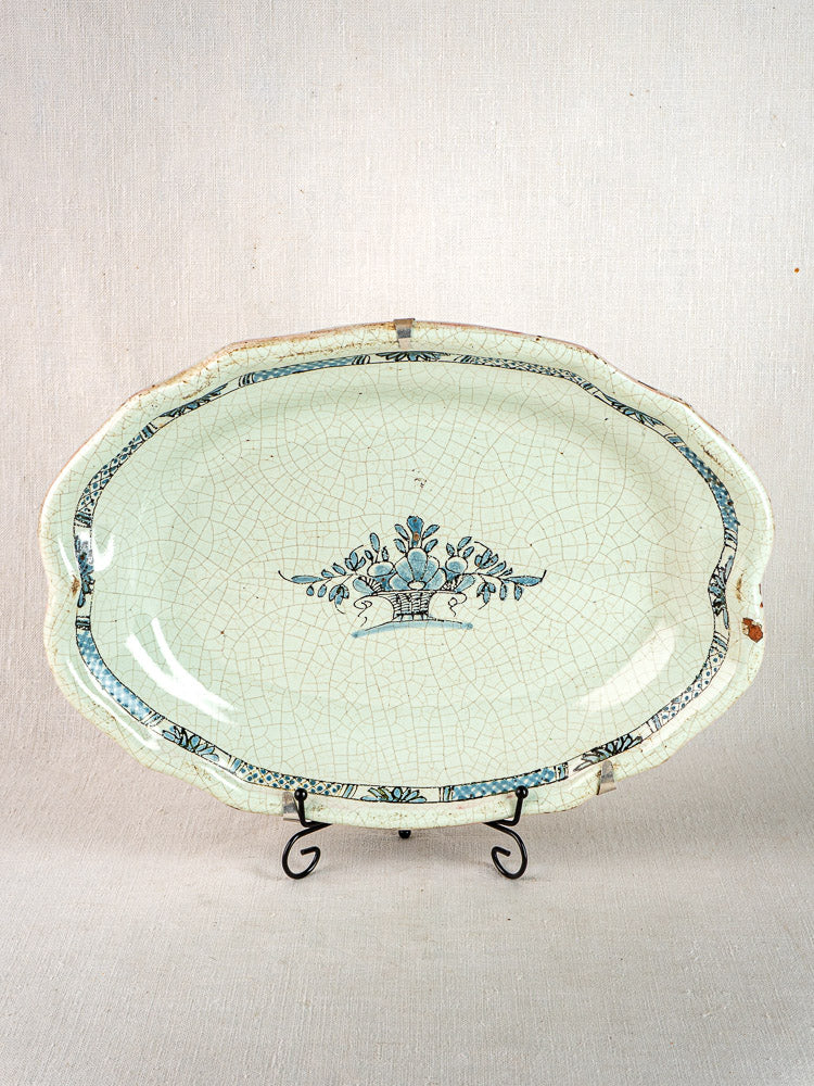 Pair of antique French Cul Noir faience platters with blue floral motifs on black metal stands.