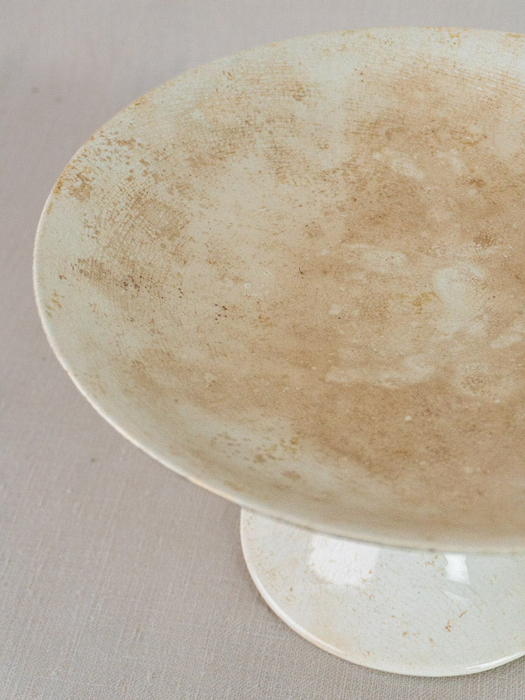 Longwy White Craquelé antique French faience compotier with off-white crackled glaze and stains on light gray fabric.