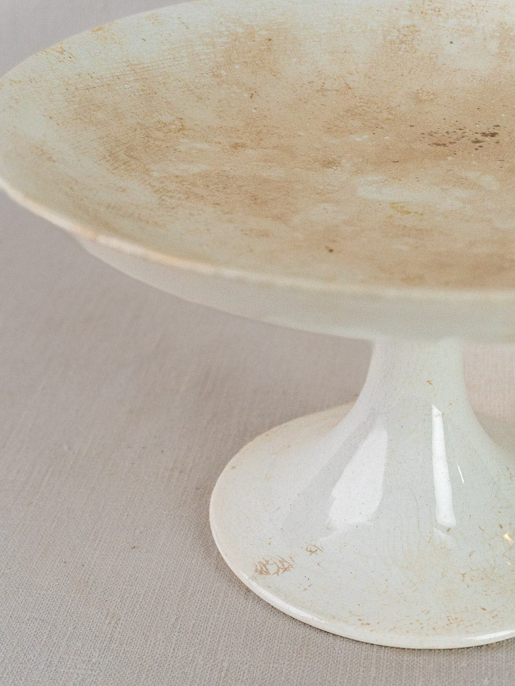 Longwy White Craquelé French faience compotier with worn, stained surface on a pale background.
