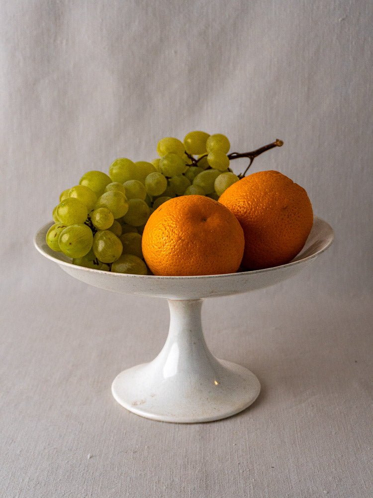 Antique French Longwy White Craquelé faience compotier displayed with oranges and green grapes.