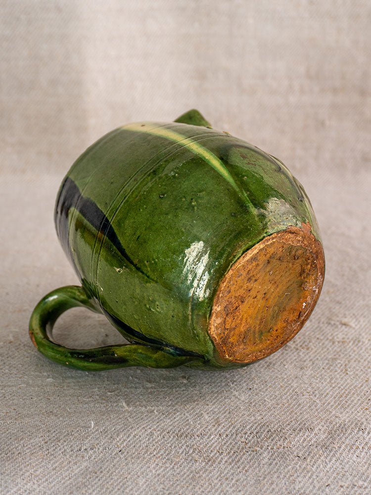 Antique French Jaspe pottery pitcher from Savoie with green glaze, floral motif, and handle on neutral linen cloth.