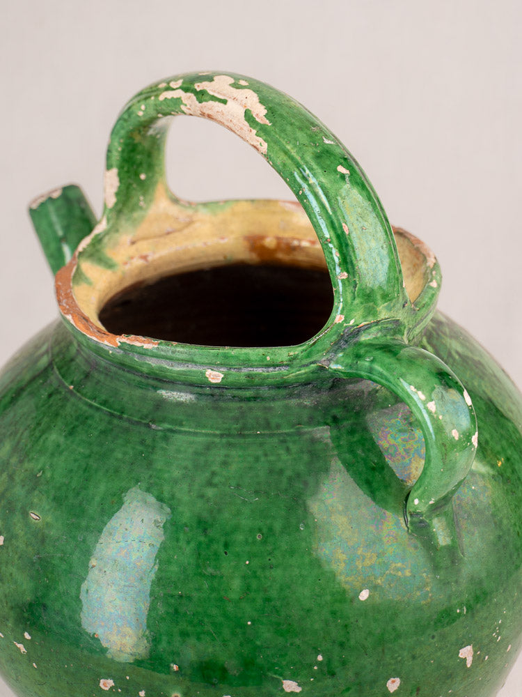 Antique French green glazed gargoulette with two handles and spout, chipped glaze revealing rustic earthenware clay.