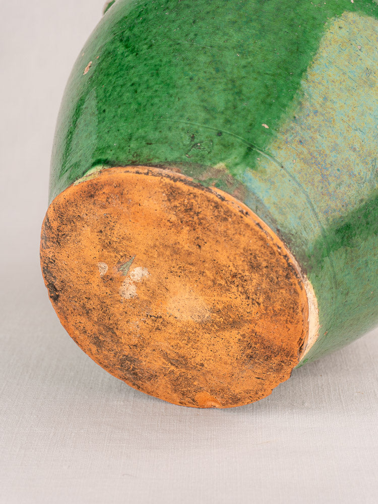 Antique French green-glazed Provençal earthenware gargoulette with round form and textured unglazed base on light fabric.