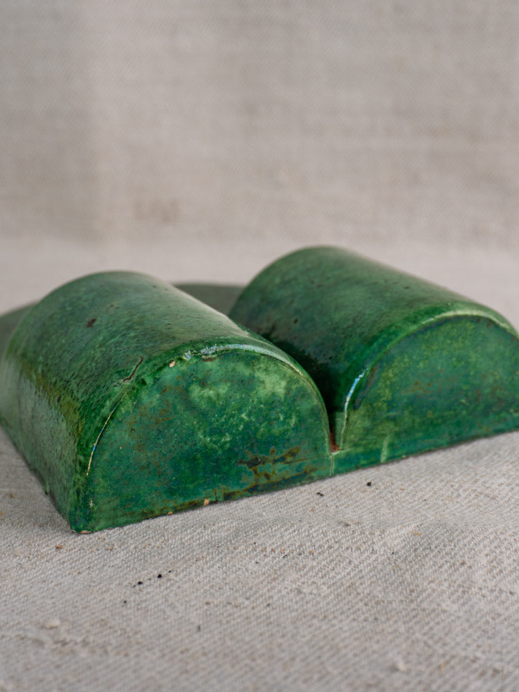 Antique French green glazed earthenware wall utensil holder, classic terre vernissée, on beige textured fabric.
