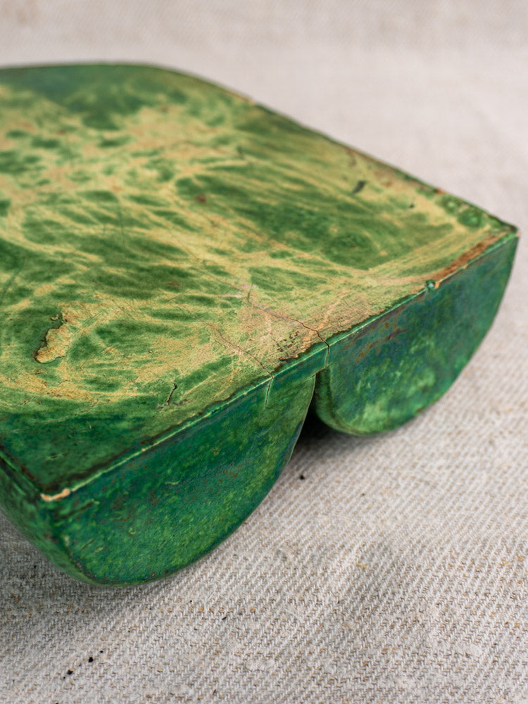 Antique French green glazed earthenware wall utensil holder, rounded edges, gently worn, on beige fabric.