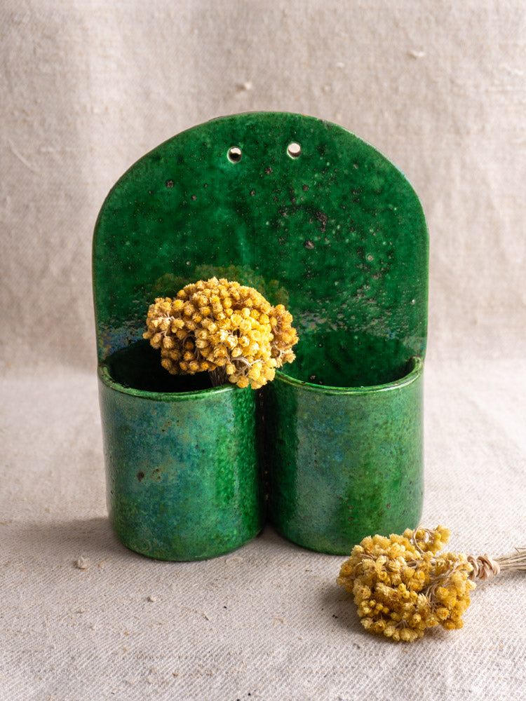 Antique French green earthenware wall utensil holder, late 19th–early 20th century, on neutral fabric background.