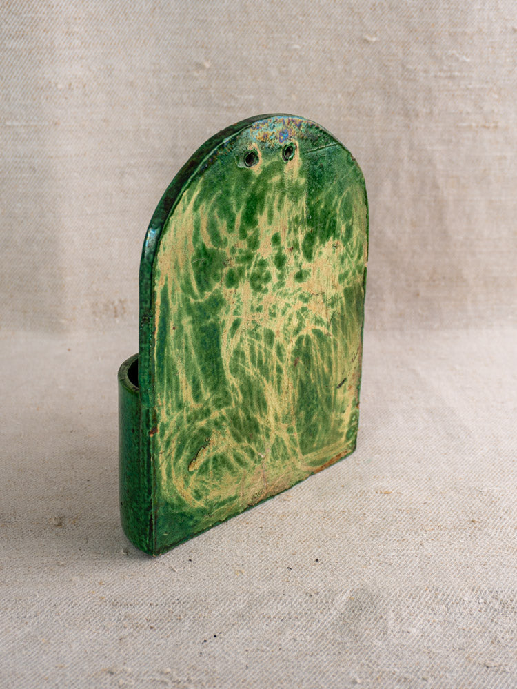 Antique French green-glazed earthenware wall utensil holder, late 19th–early 20th century, aged patina, on beige fabric.