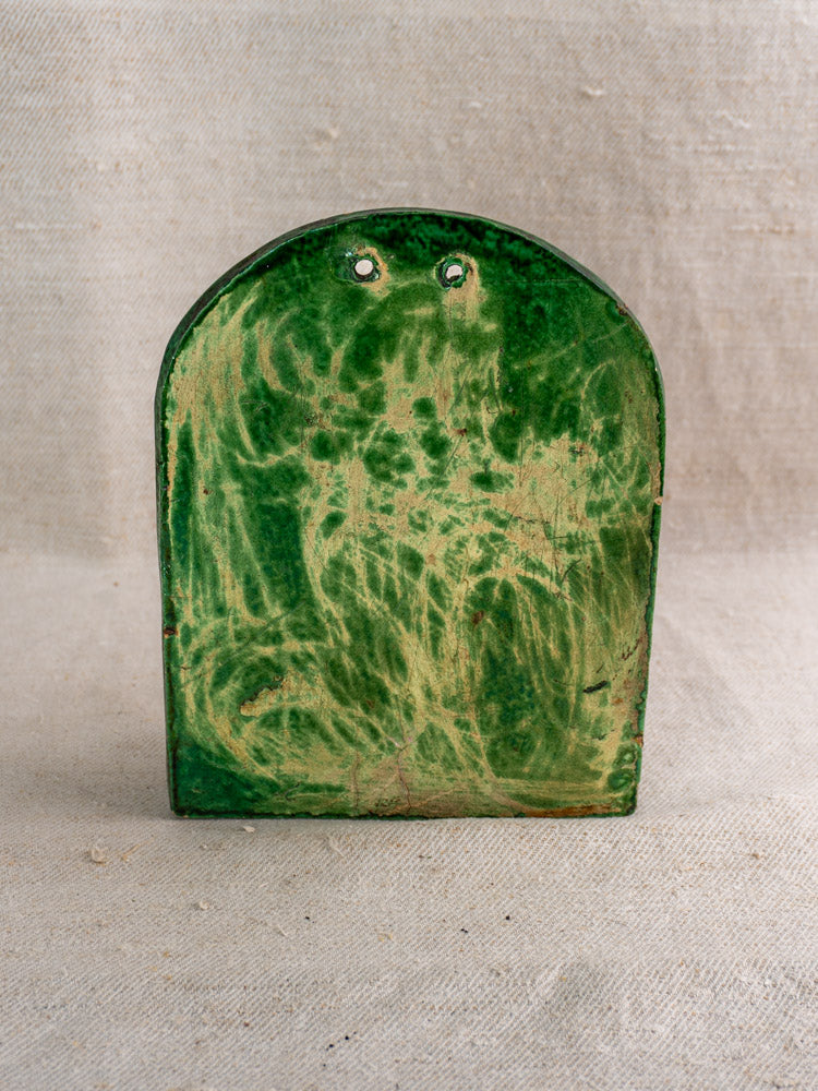 Antique French green glazed earthenware wall utensil holder with arched shape, two holes; on beige textured fabric.