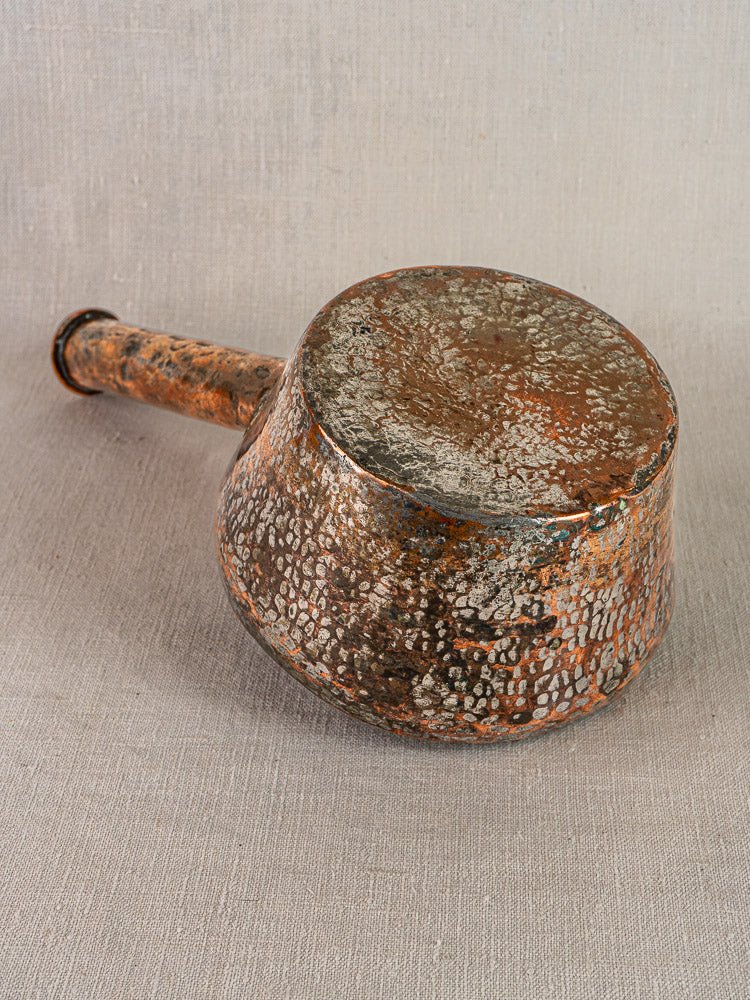 Antique French hand-forged copper saucepan with sturdy handle, rich patina, and heavy tarnish.