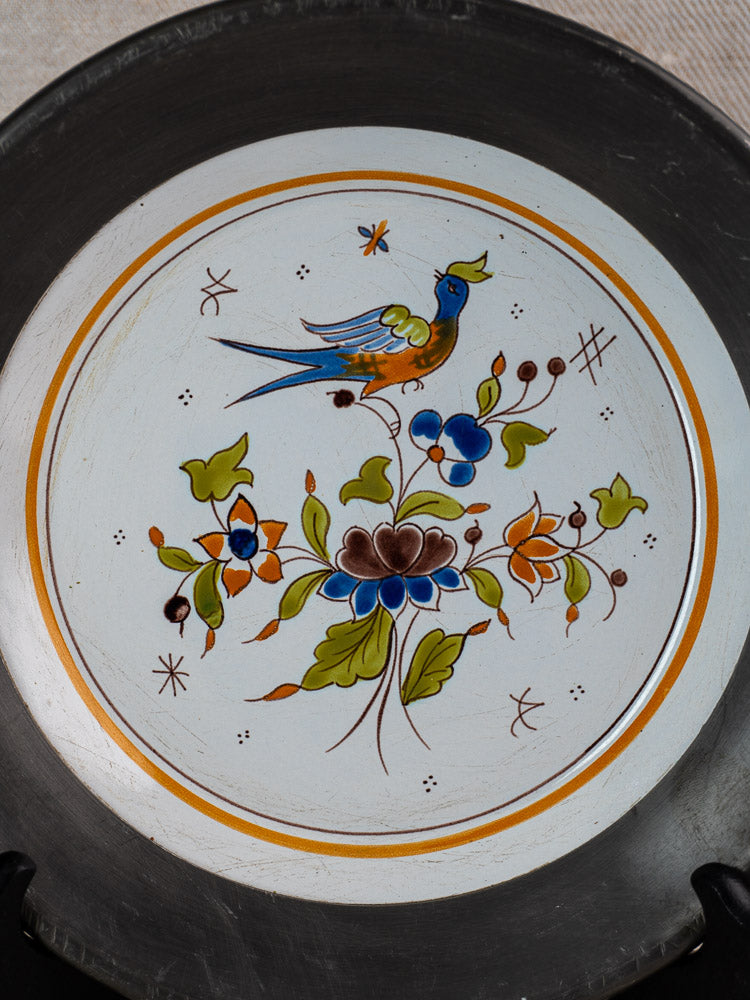 French faience wall plate in Moustiers style with hand painted bird, flowers, and orange-brown border.