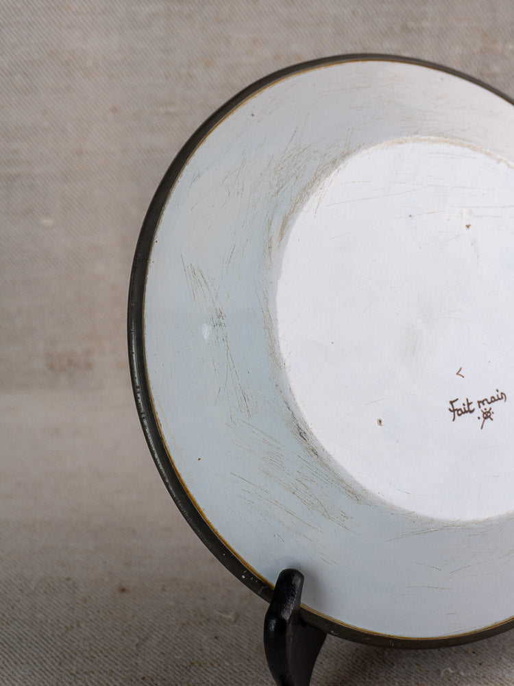 Back of vintage French faience wall plate, Moustiers style, with “Fait main”; visible scratches.