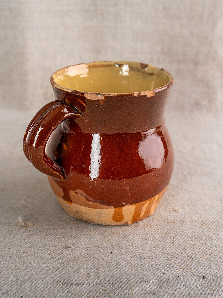19th century French earthenware pichet with half-dipped brown glaze and sturdy handle on beige textured fabric.