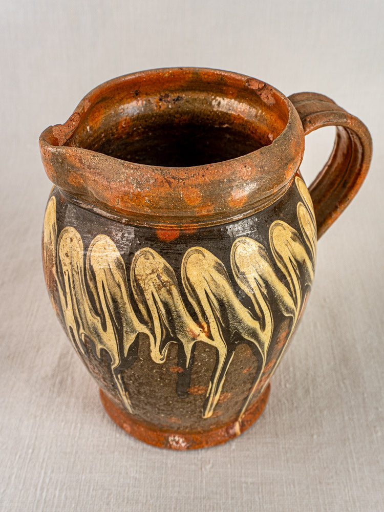Antique French Savoie ceramic pitcher with brown glaze and cream dripped rim patterns.