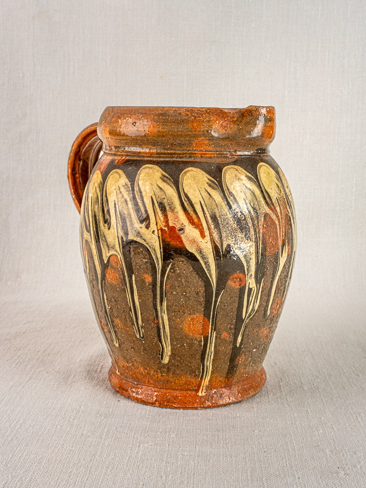 Antique French Savoie Pichet Jaspé in rustic brown ceramic with yellow cream slipware glaze on neutral fabric.