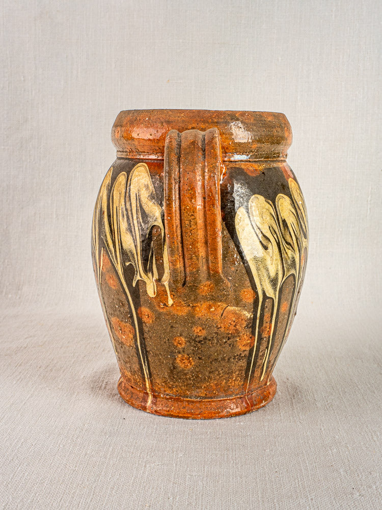Antique French Pichet Jaspé slipware pottery with brown ceramic, yellow glaze patterns, and textured handles on neutral fabric.