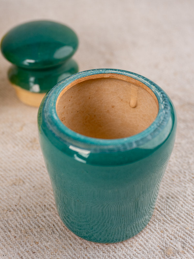 Vintage French Maille mustard pot in teal and yellow with matching lid on beige textured surface.