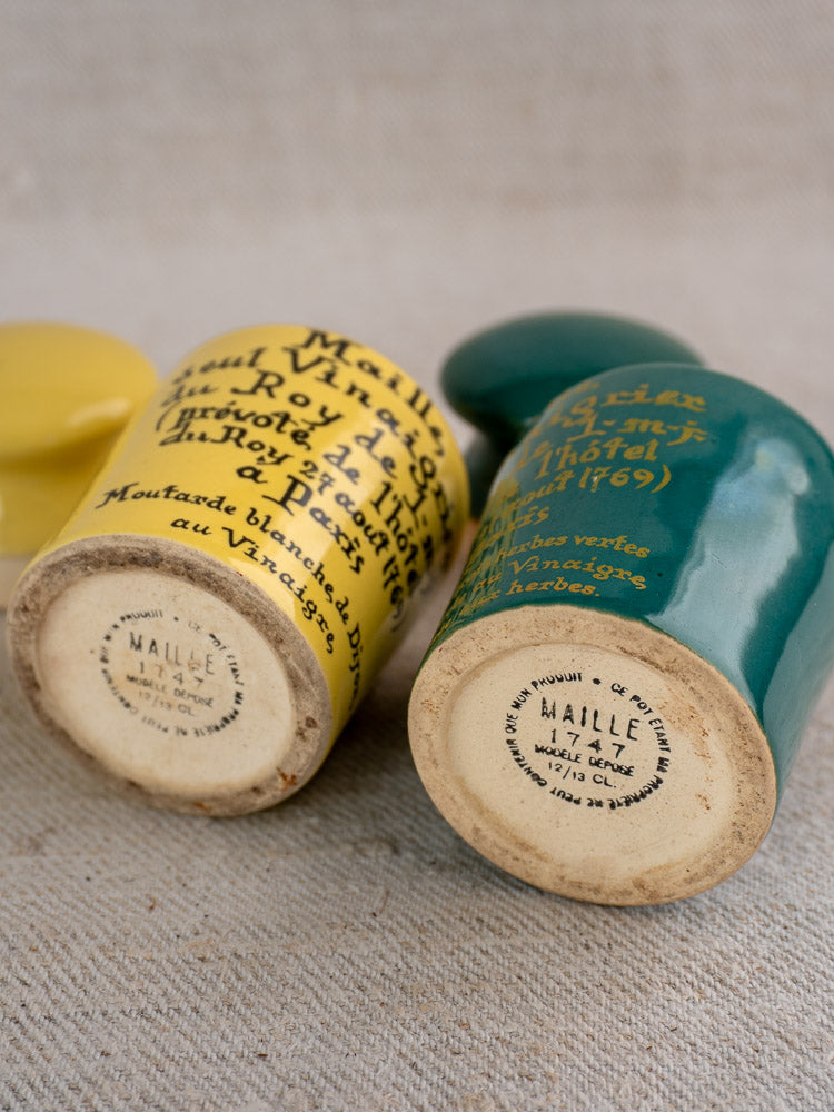 Vintage French Maille mustard pots, teal and yellow, with bases showing “Dijon mustard” labels.