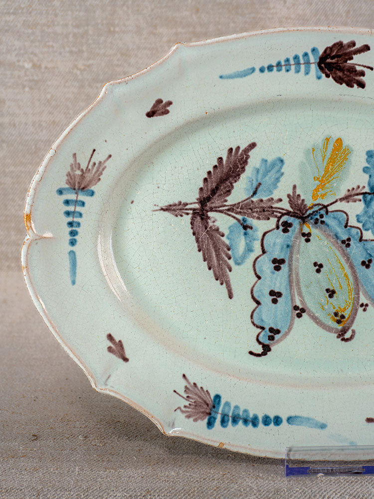 Antique French Cul Noir faience platter with scalloped edges, hand-painted florals, and visible aging and crackling.