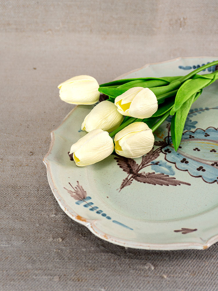 Antique French Cul Noir faience platter with blue and brown patterns, tulips on textured beige surface.