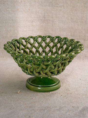 Vintage French Pichon Uzès basket with green Provençal glaze, lattice design, round base; neutral fabric background.
