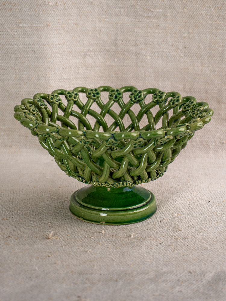 Vintage French Pichon Uzès basket with green glaze and lattice bowl on pedestal, atop textured beige fabric.