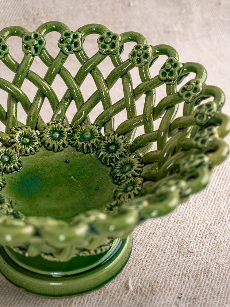 Vintage French Pichon Uzès woven basket with green glaze, lattice design, and floral rim on beige textured fabric.
